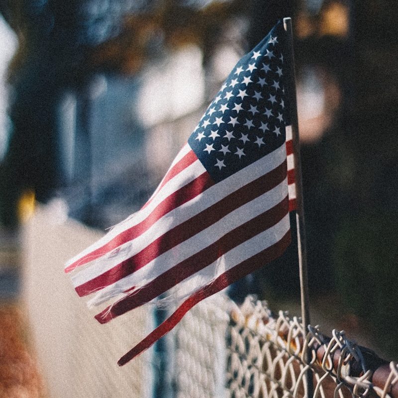 us a flag on gray metal fence during daytime